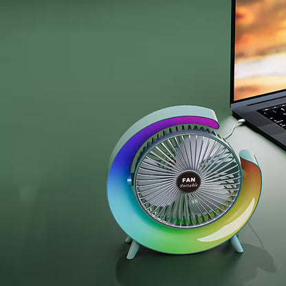 Colorful portable fan on a desk next to a laptop with a green background