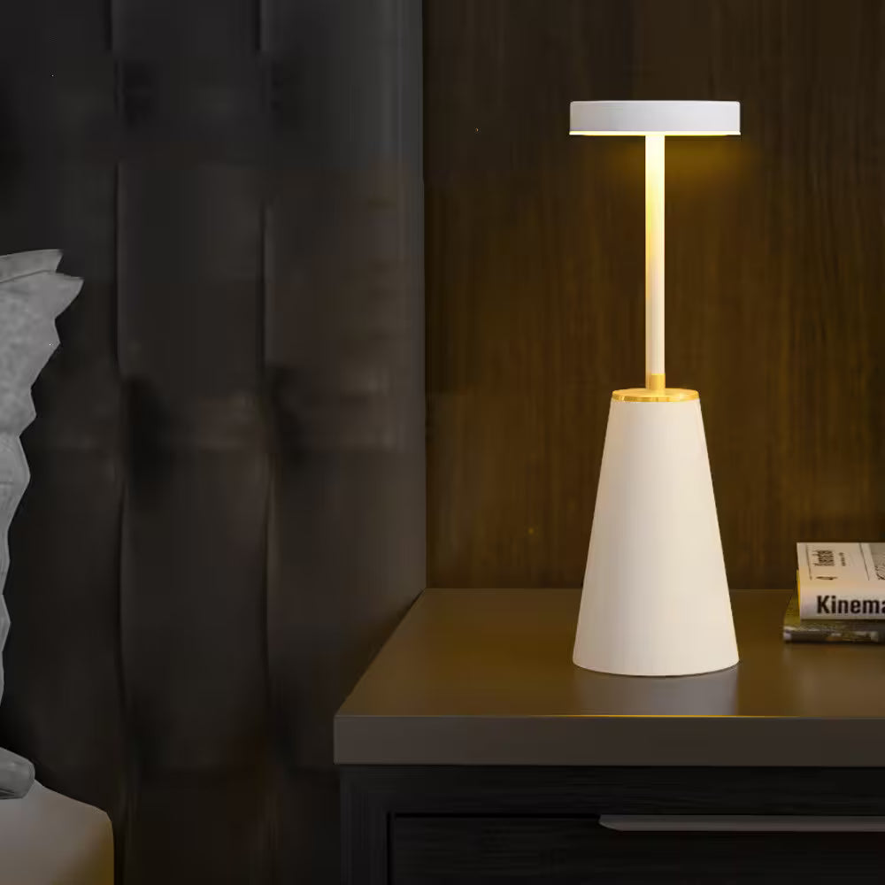 Modern table lamp with a white base and gold accent on a dark surface.