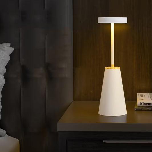 Modern table lamp with a white base and gold accent on a dark surface.