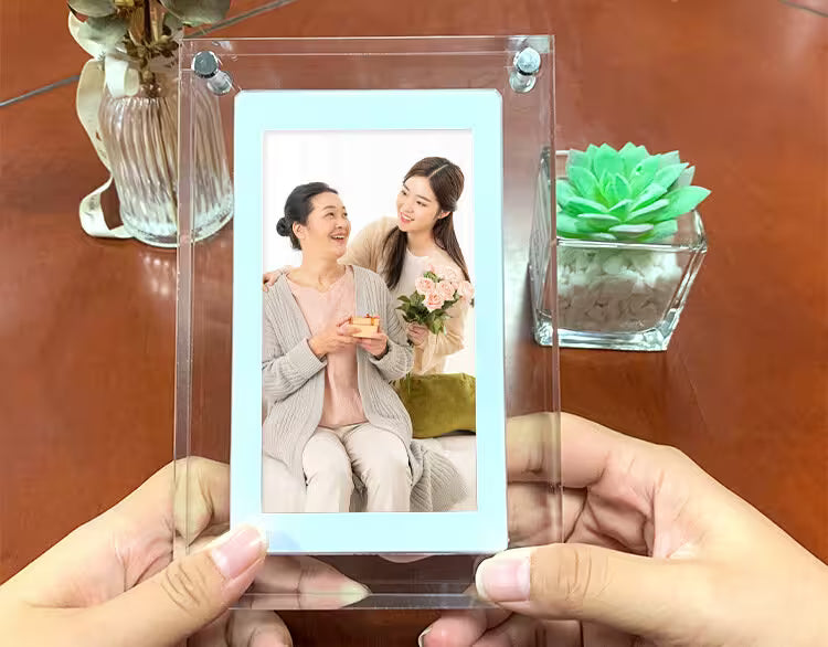 Clear acrylic photo frame with a picture of two women on a wooden surface with plants.