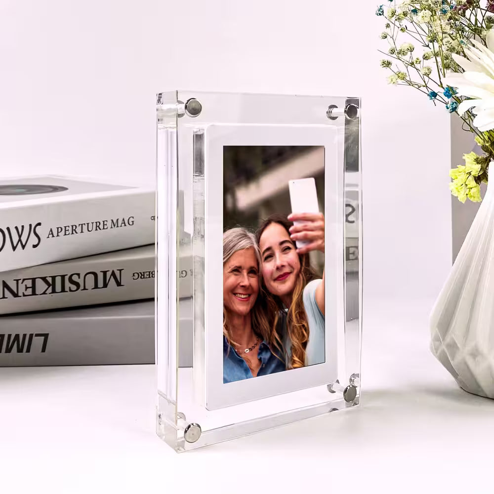Clear photo frame displaying a selfie of two women, with books and a vase in the background.