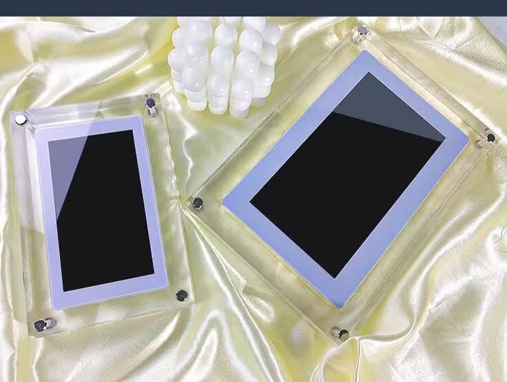 Two black rectangular objects in clear frames on a textured beige surface.