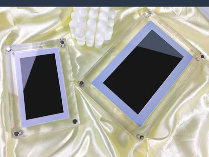 Two black rectangular objects in clear frames on a textured beige surface.