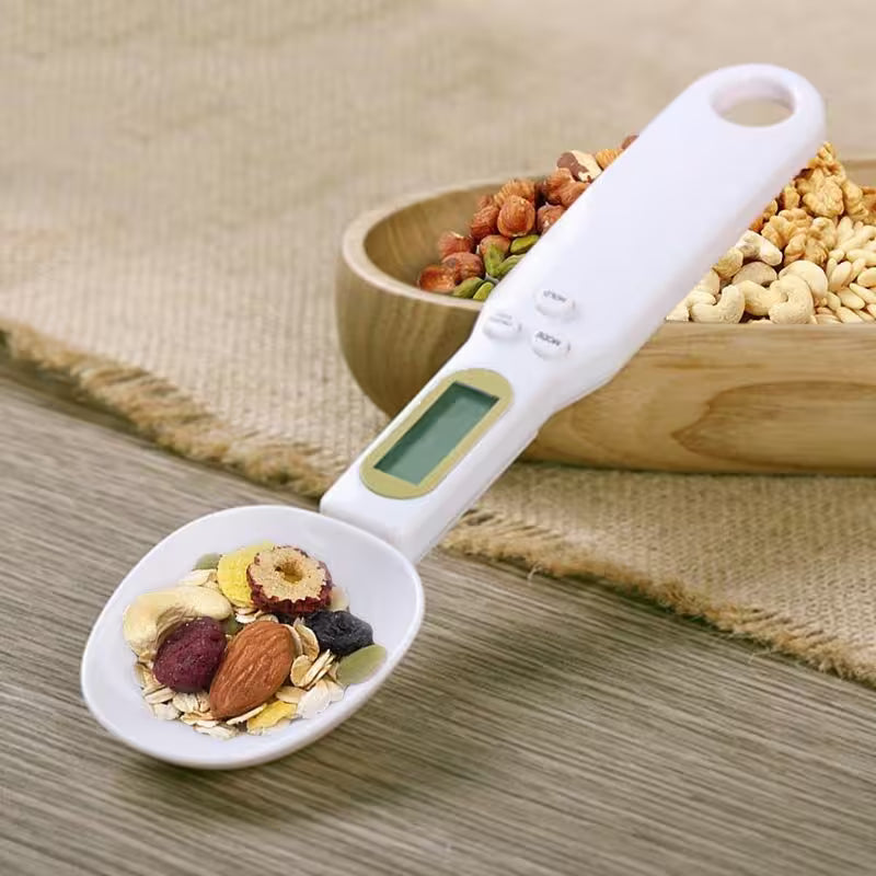 Digital measuring spoon with a bowl of mixed nuts and seeds on a wooden surface