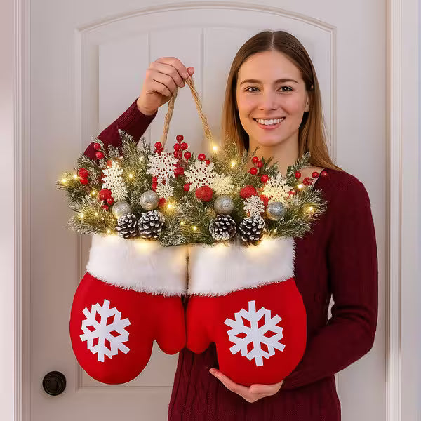 Person holding a decorative item resembling red mittens with snowflakes, filled with Christmas lights and ornaments.