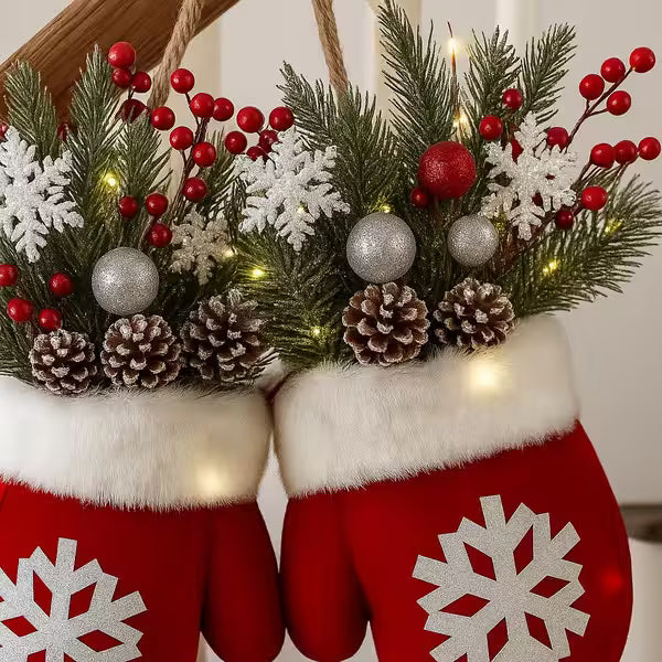 Red mittens with white snowflake patterns holding a festive wreath with greenery, berries, and ornaments.