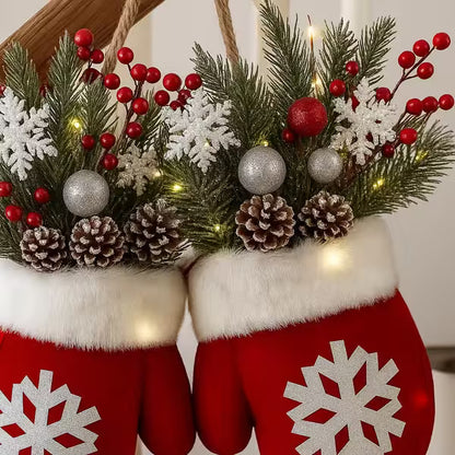 Red mittens with white snowflake patterns holding a festive wreath with greenery, berries, and ornaments.