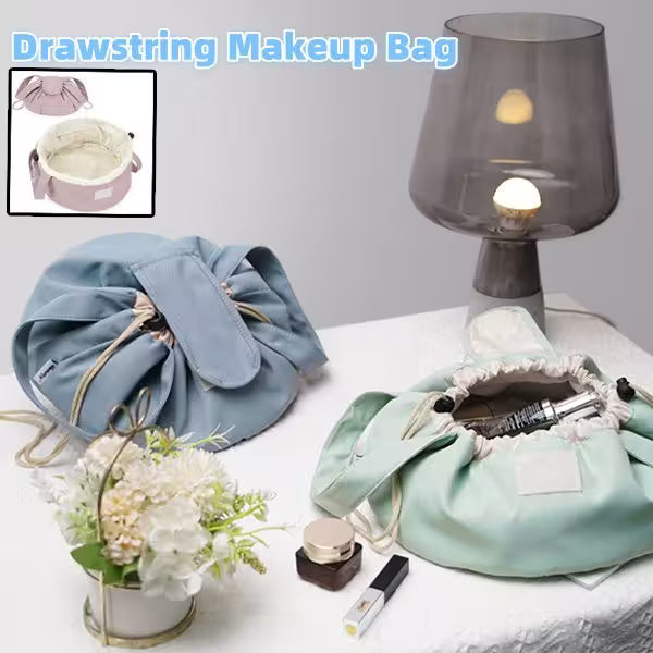 Drawstring makeup bag with cosmetic items on a table next to a lamp and flowers.