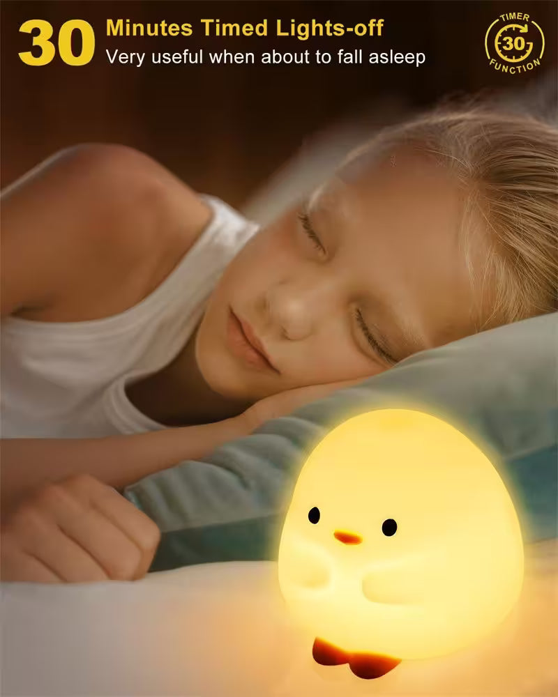 Child sleeping with a glowing chick-shaped night light on a dark background