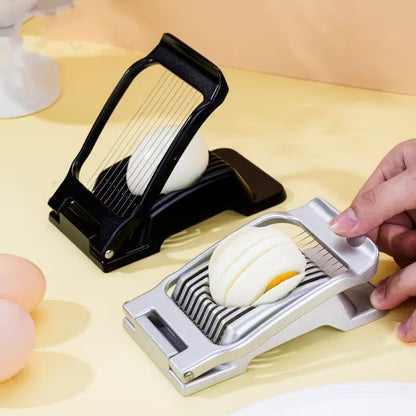 Egg slicer being used to slice an egg on a light wooden surface.