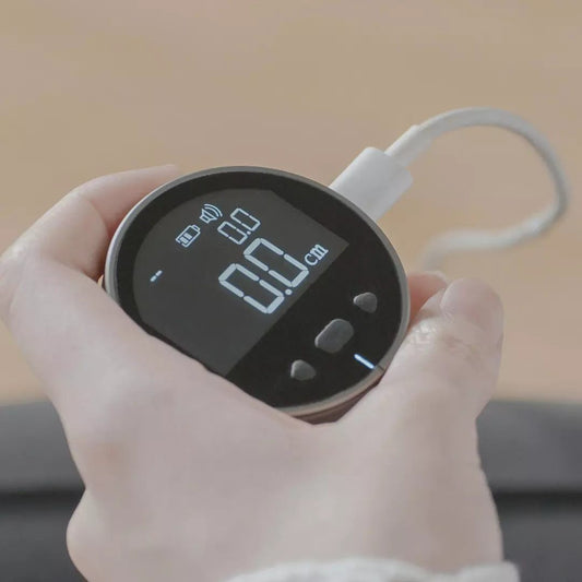 Hand holding a digital device with a screen displaying numbers, against a neutral background.