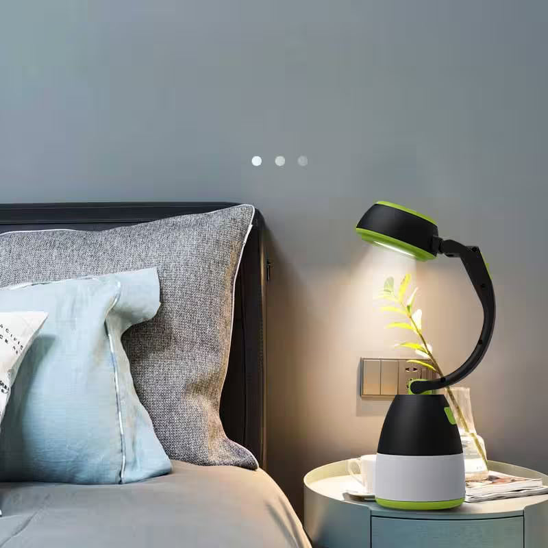 Black and green lamp on a nightstand next to a bed with pillows.