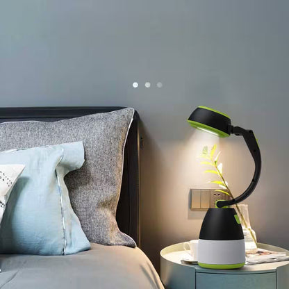 Black and green lamp on a nightstand next to a bed with pillows.