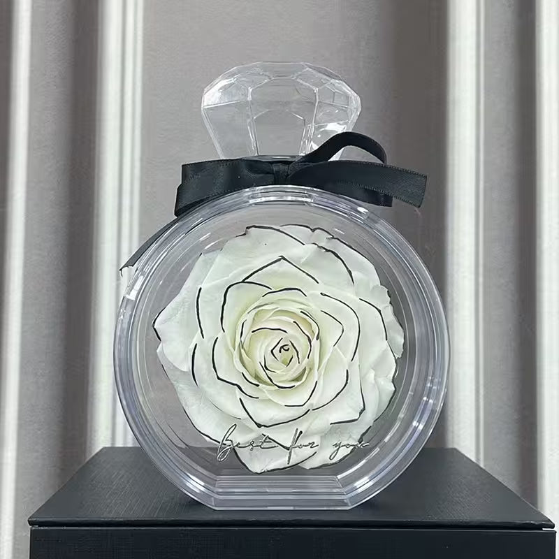 Preserved white rose in a clear container with a black bow on a gray background