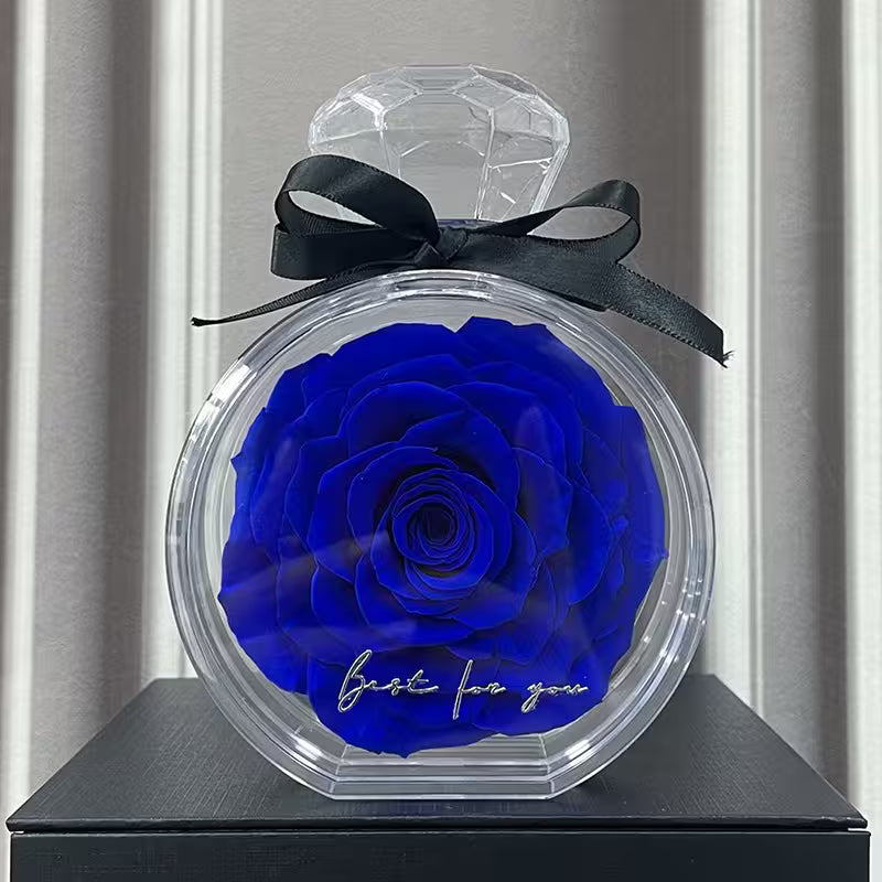Blue rose in a transparent container with a black bow on a gray surface.