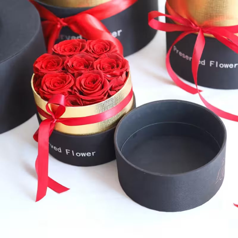 Heart-shaped box of red roses with a black lid on a white background