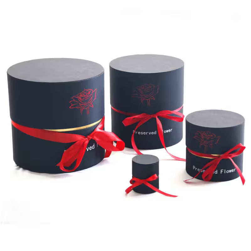 Set of cylindrical boxes with red ribbons and floral designs on a white background