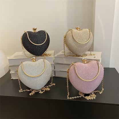 Four heart-shaped handbags in black, white, pink, and gold on a dark surface with a light gray background.