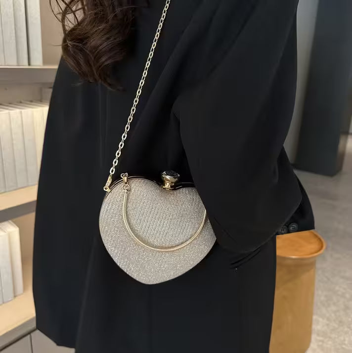 Person wearing a black coat with a silver glittery handbag on a blurred indoor background