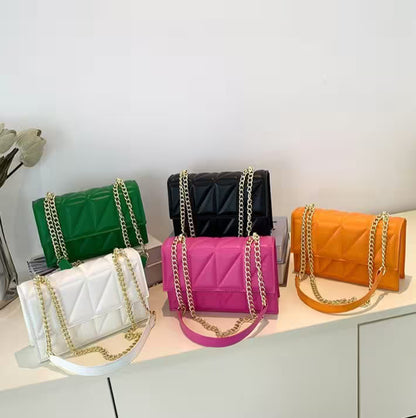 Five colorful handbags with gold chains on a light surface.