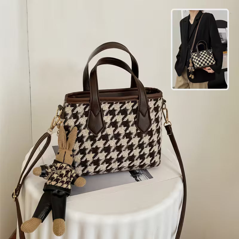 Houndstooth patterned handbag with brown leather accents on a white surface.