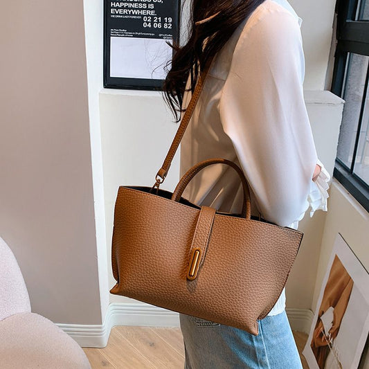Person holding a brown handbag indoors