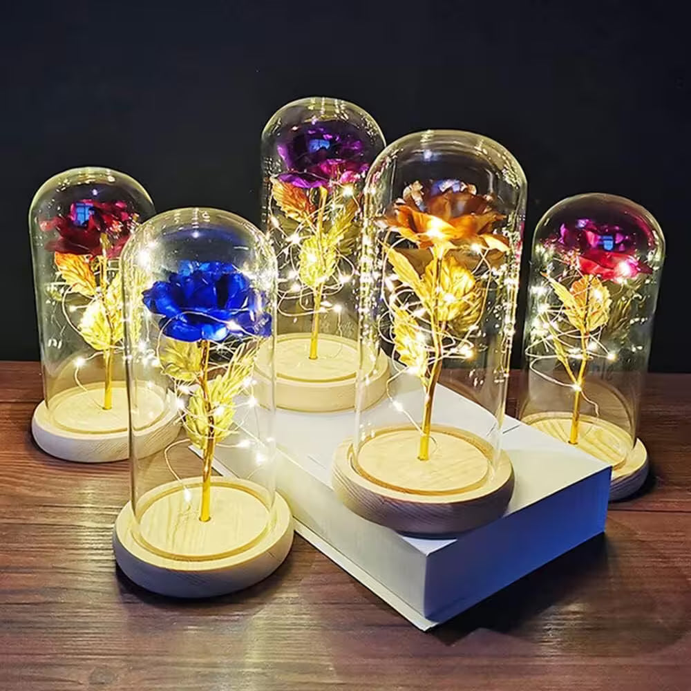 Decorative lights with colored flowers inside glass domes on a wooden surface.