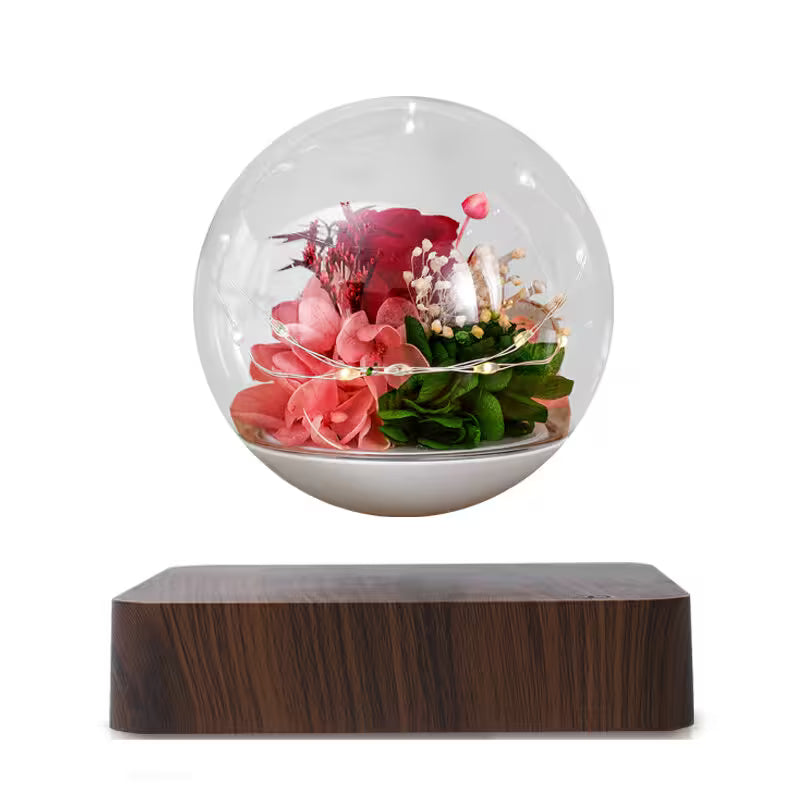 Decorative glass sphere with flowers on a wooden base against a white background