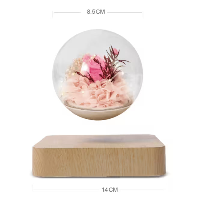 Decorative item with a transparent sphere containing pink flowers on a wooden base, with dimensions indicated.