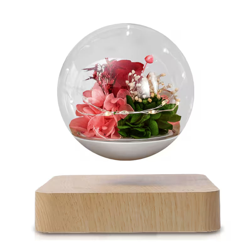 Decorative glass sphere with flowers on a wooden base against a white background