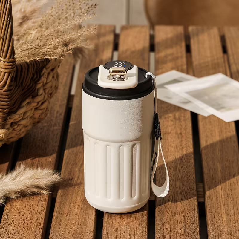 White insulated coffee cup with black lid on a wooden surface