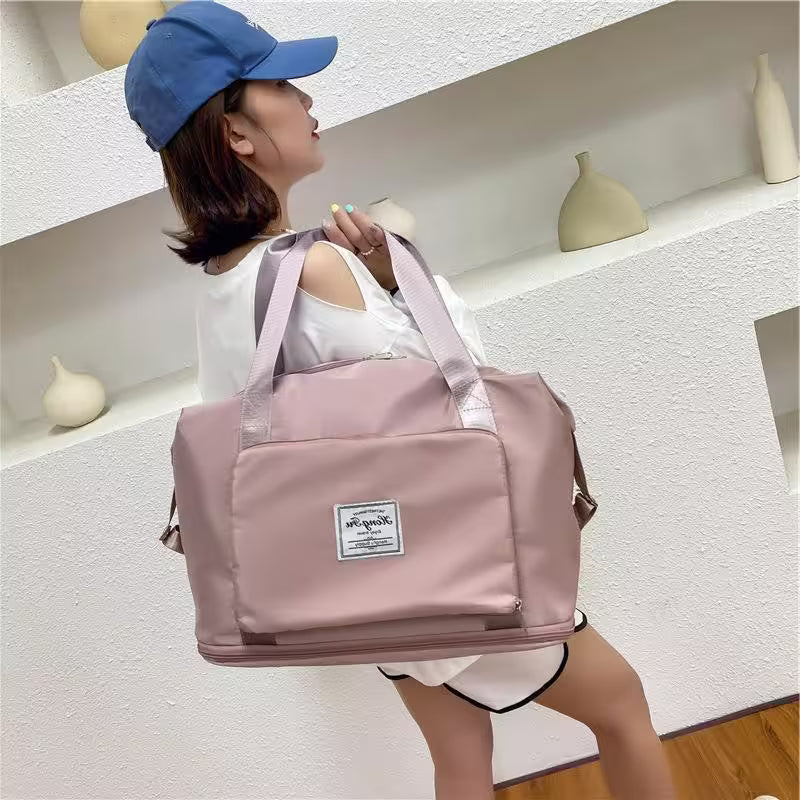 Person holding a pink duffel bag with a white label in a minimalistic indoor setting.