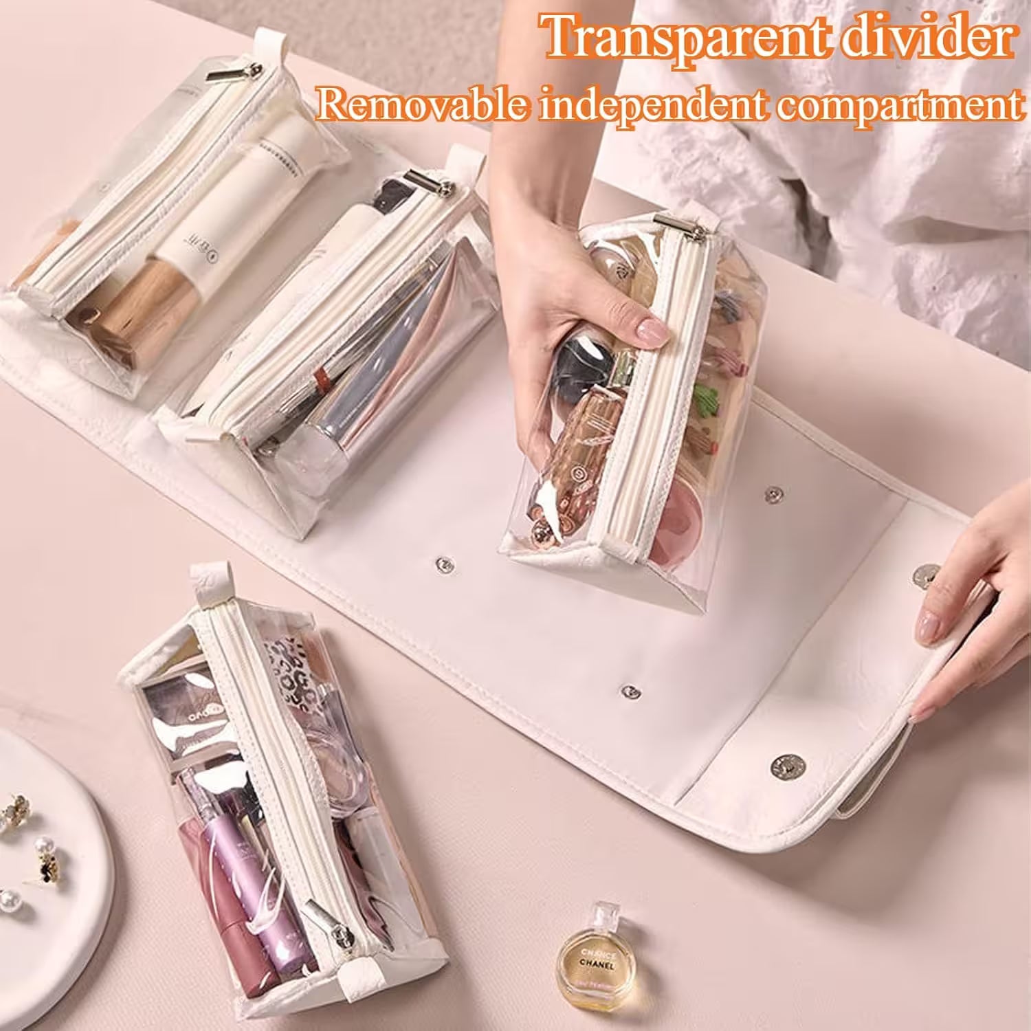 Cosmetic bag with transparent divider and removable independent compartment on a light pink surface.