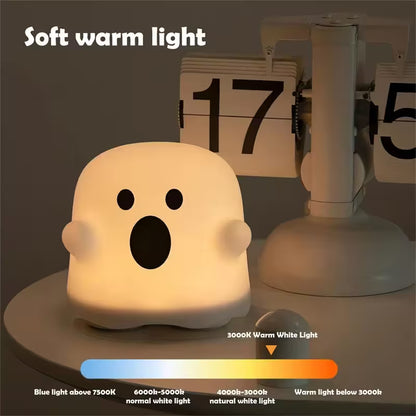 Ghost-shaped night light emitting a soft warm light, placed on a surface with a calendar in the background.