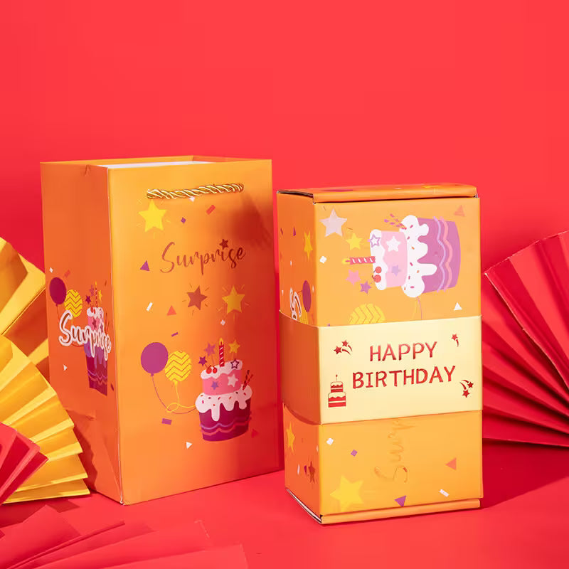 Orange birthday gift bag and box with 'Surprise' and 'Happy Birthday' text on a red background
