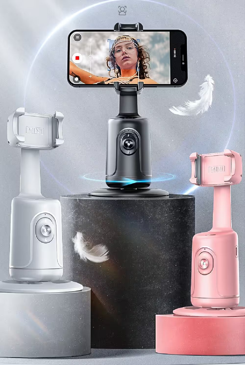 Three smartphone holders in gray, black, and pink on a gray background with a phone displaying a video.