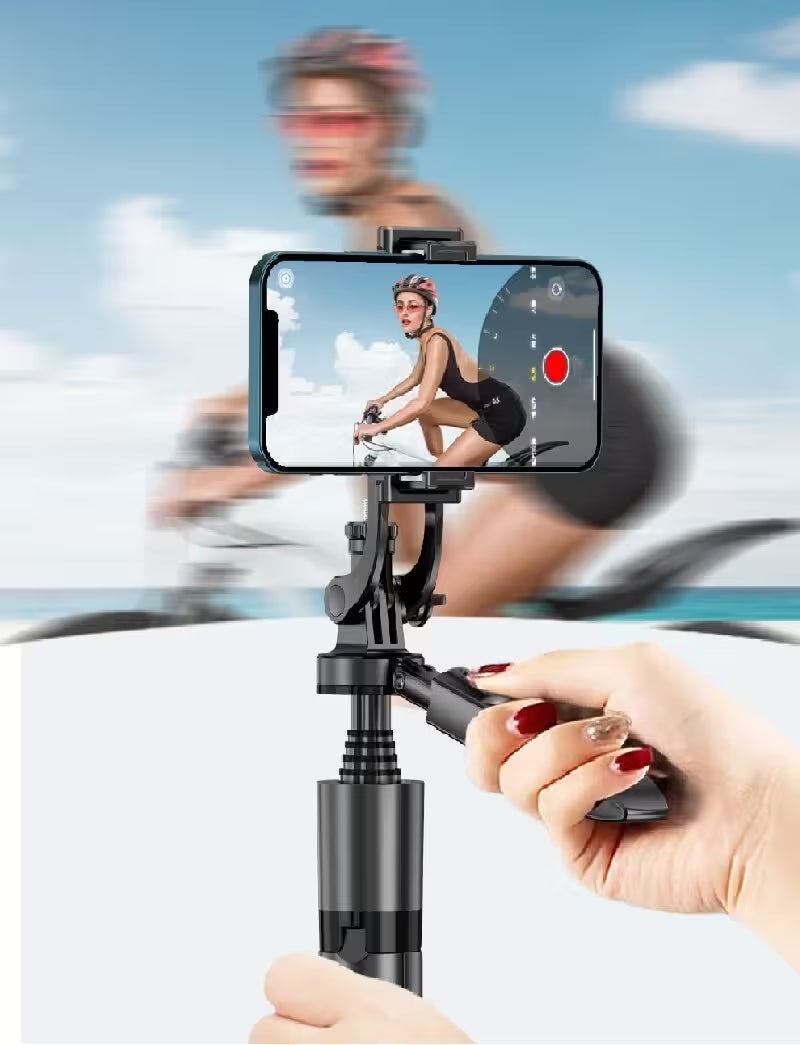 Hand holding a smartphone with a gimbal stabilizer, showing a cyclist on screen against a blurred outdoor background.