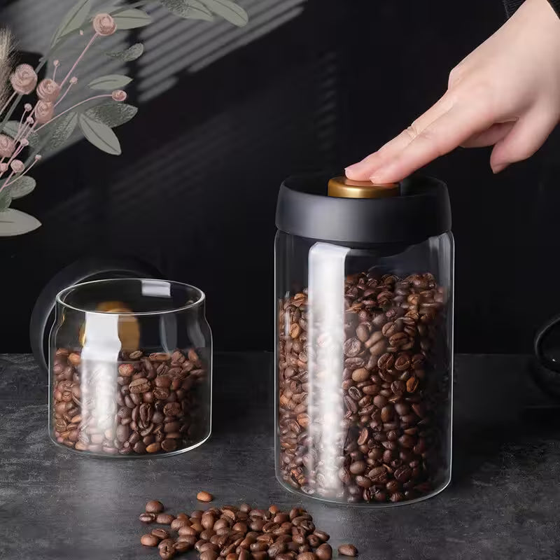 Glass jar with coffee beans and a hand reaching to open it on a dark surface.
