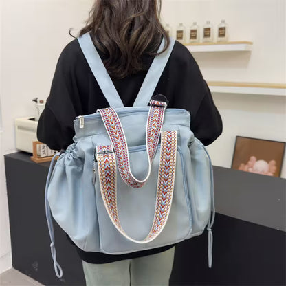 Person wearing a light blue backpack with decorative handles in an indoor setting