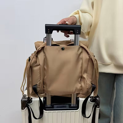 Person holding a beige backpack on top of a white suitcase with a plain background