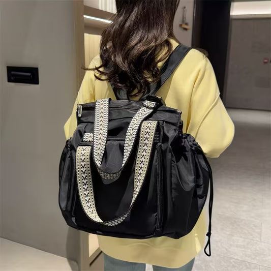 Person wearing a black backpack with white drawstring in an indoor setting