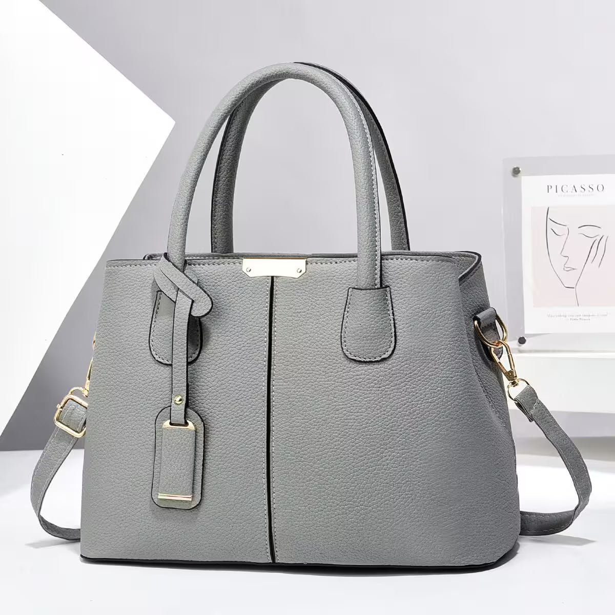 Gray handbag with gold accents on a white background