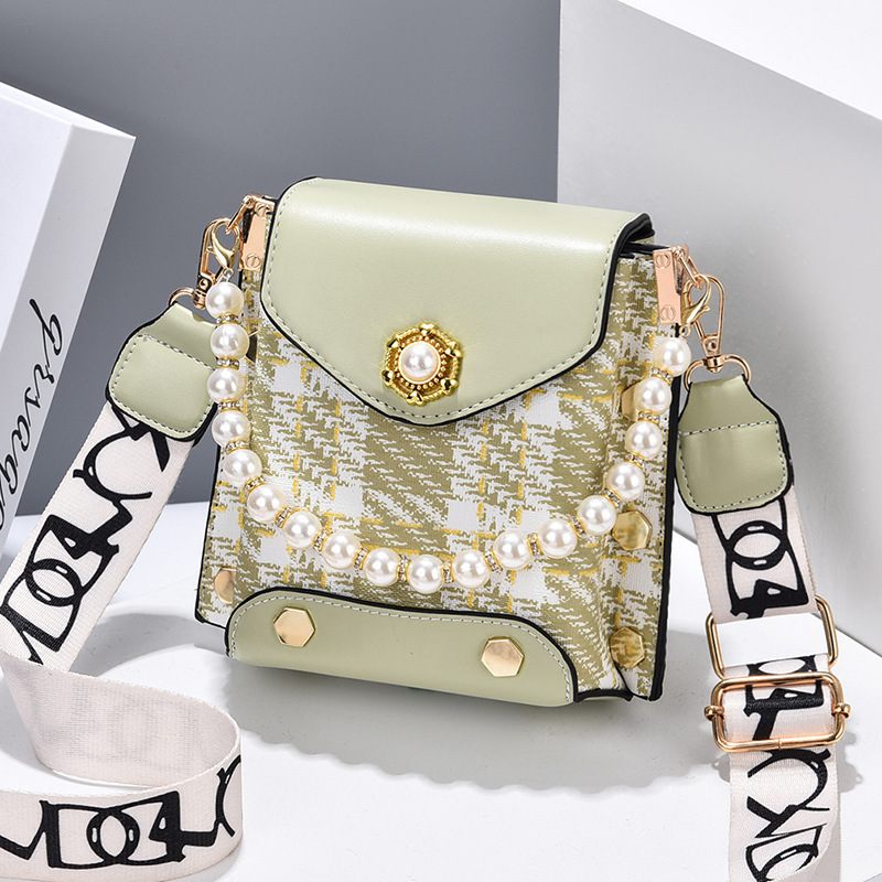 Green handbag with pearl embellishments on a light gray background