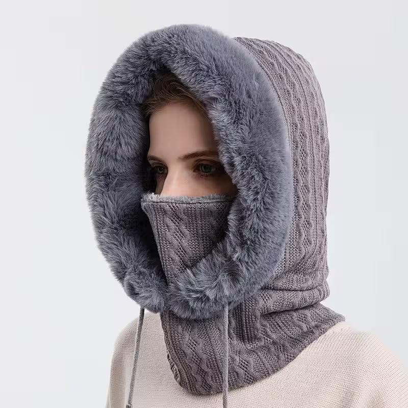 Person wearing a gray knitted balaclava with fur trim on a white background