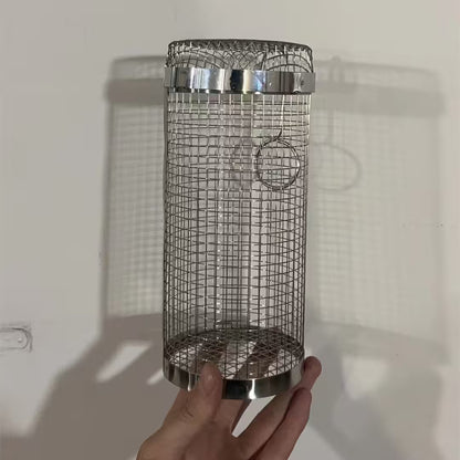 Metallic bird feeder held by a hand against a plain background