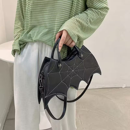 Person holding a black bat-shaped handbag with a minimal background