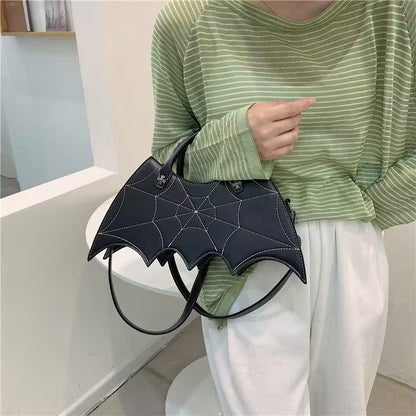 Person holding a black bat-shaped handbag in a minimal indoor setting