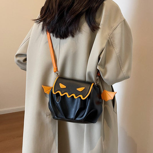 Person wearing a black bag with pumpkin design on a plain background