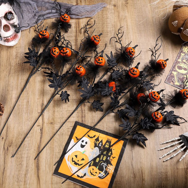Halloween-themed decorations including black stems with orange pumpkins, a skull, and a card with ghost and pumpkin design on a wooden surface.