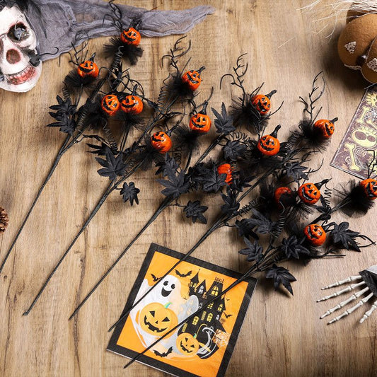 Halloween-themed decorations including black stems with orange pumpkins, a skull, and a card with ghost and pumpkin design on a wooden surface.